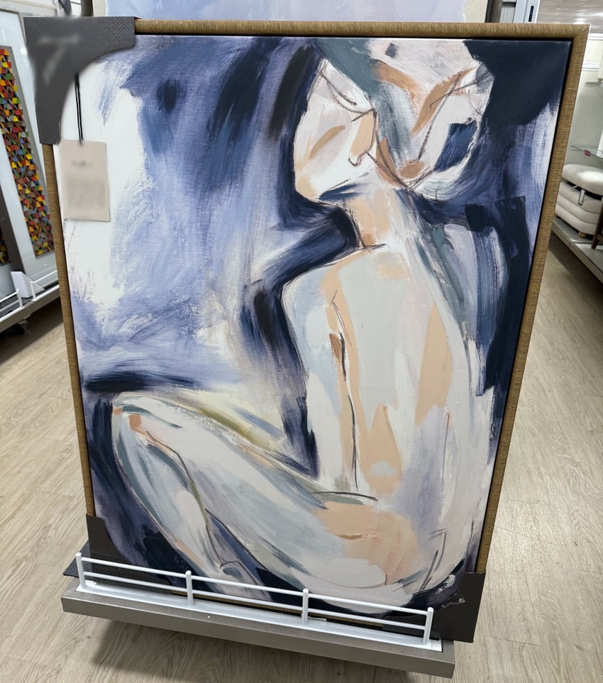 A bad painting (mass produced) of a seated woman at a home goods store.