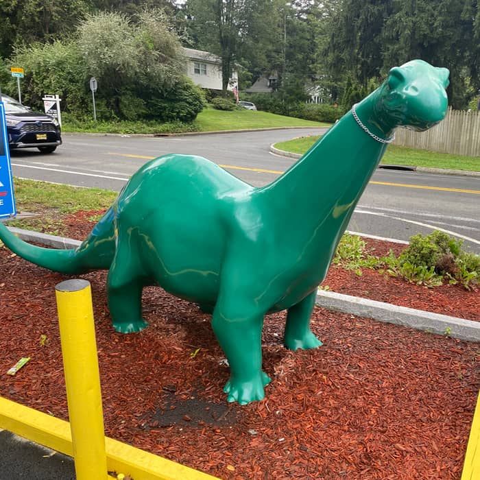 A green dinosaur sculpture seen roadside